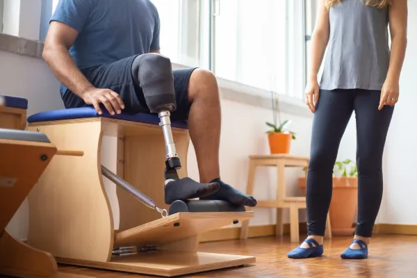 A man sitting with a prosthetic leg while a clinician stands nearby